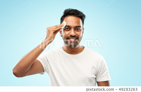 smiling indian man cleaning face with cotton pad 49283263