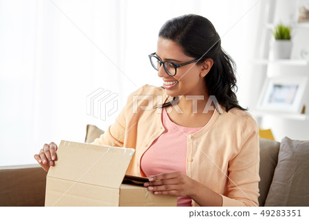 happy indian woman opening parcel box at home 49283351