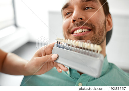 dentist choosing tooth color for patient at clinic 49283367