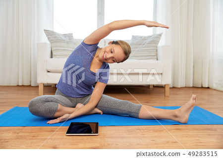 woman with tablet computer doing yoga at home 49283515
