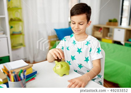little boy putting coin into piggy bank at home 49283852