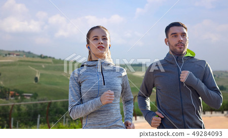 happy couple with earphones running outdoors happy couple with earphones running outdoors 49284093
