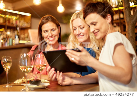 women with tablet pc at wine bar or restaurant 49284277