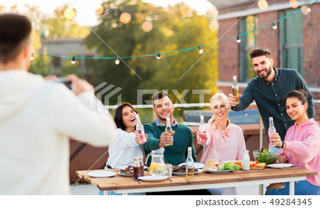 happy friends photographing at rooftop party happy friends photographing at rooftop party 49284345