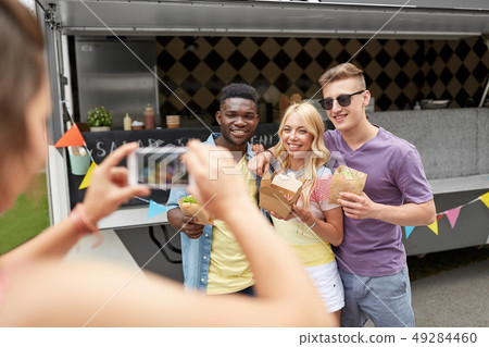 woman photographing friends eating at food truck 49284460
