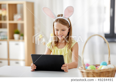 happy girl with tablet pc and easter eggs at home 49284491