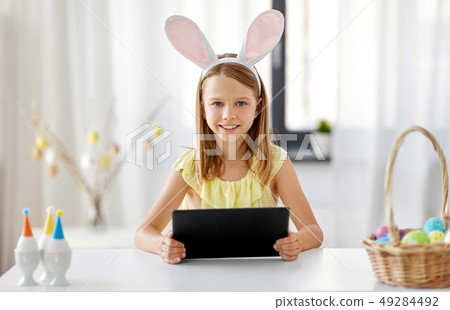 happy girl with tablet pc and easter eggs at home happy girl with tablet pc and easter eggs at home 49284492