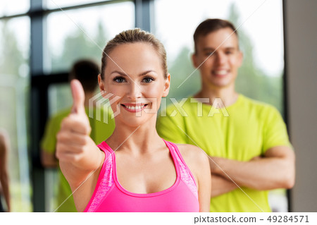 smiling man and woman showing thumbs up in gym smiling man and woman showing thumbs up in gym 49284571