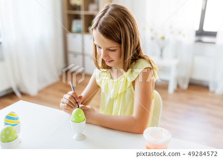 happy girl coloring easter eggs at home 49284572