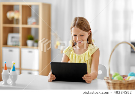 happy girl with tablet pc and easter eggs at home happy girl with tablet pc and easter eggs at home 49284592