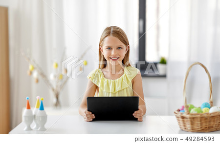 happy girl with tablet pc and easter eggs at home happy girl with tablet pc and easter eggs at home 49284593