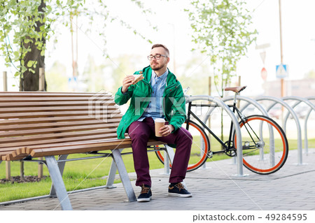 young man or hipster with coffee eating sandwich young man or hipster with coffee eating sandwich 49284595
