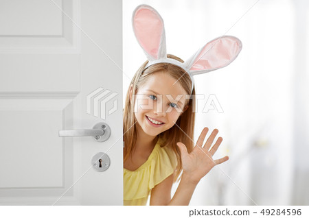 happy girl with easter bunny ears peeking out door happy girl with easter bunny ears peeking out door 49284596