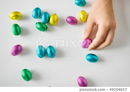 hand of child with chocolate easter eggs in foil hand of child with chocolate easter eggs in foil 49284657
