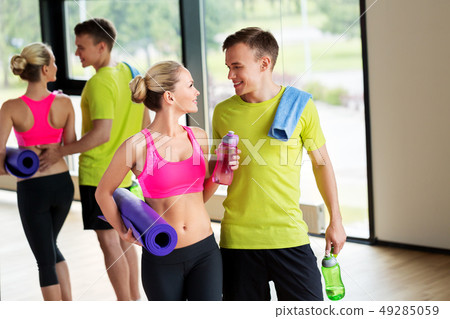 couple with bottles, exercise mat and towel in gym couple with bottles, exercise mat and towel in gym 49285059
