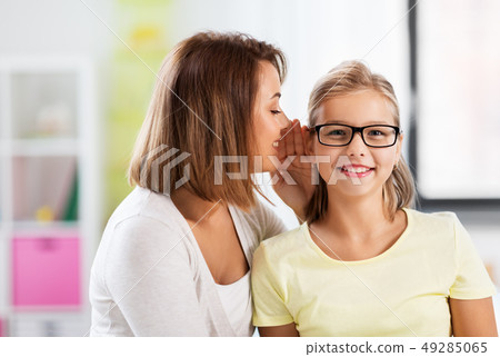 happy mother whispering secret to daughter at home happy mother whispering secret to daughter at home 49285065