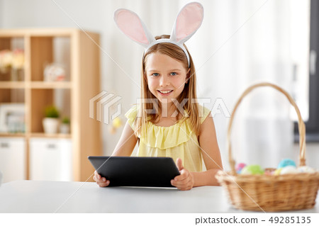 happy girl with tablet pc and easter eggs at home happy girl with tablet pc and easter eggs at home 49285135