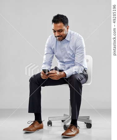 smiling indian businessman sitting on office chair smiling indian businessman sitting on office chair 49285196