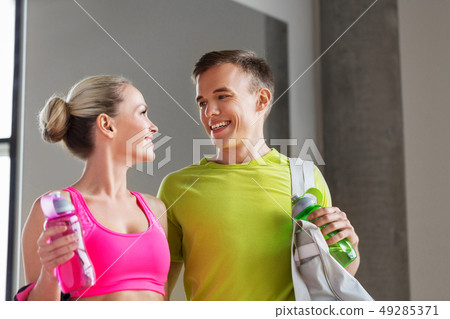 sportive couple with water bottles and bag in gym sportive couple with water bottles and bag in gym 49285371