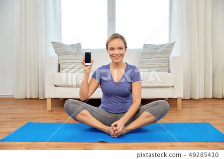 woman with smartphone doing yoga at home woman with smartphone doing yoga at home 49285410