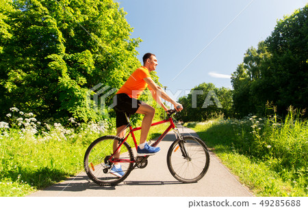 happy young man cycling by bicycle in summer park 49285688