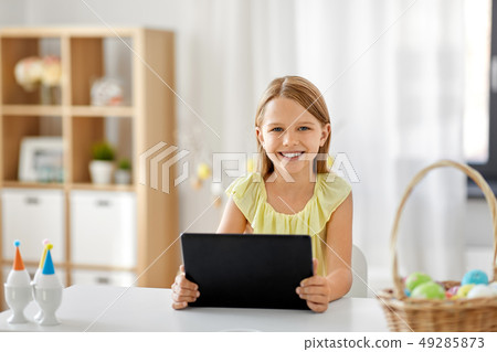 happy girl with tablet pc and easter eggs at home happy girl with tablet pc and easter eggs at home 49285873