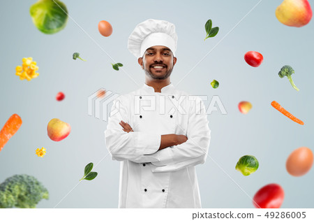 happy male indian chef in toque over vegetables happy male indian chef in toque over vegetables 49286005