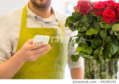 florist with smartphone and roses at flower shop 49286292
