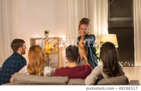 happy friends playing charades at home in evening happy friends playing charades at home in evening 49286317