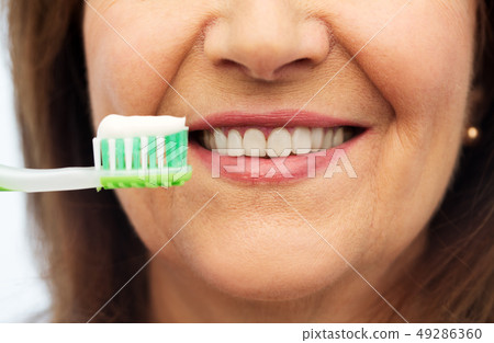 senior woman with toothbrush brushing her teeth 49286360