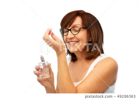 senior woman smelling perfume from her wrist senior woman smelling perfume from her wrist 49286363