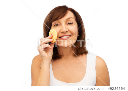 woman cleaning face with exfoliating sponge woman cleaning face with exfoliating sponge 49286364