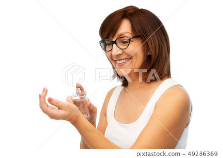 smiling senior woman spraying perfume to her wrist smiling senior woman spraying perfume to her wrist 49286369