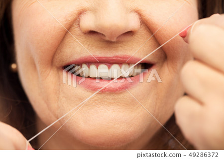 senior woman cleaning her teeth by dental floss 49286372