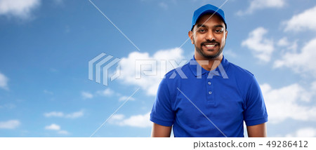 happy indian delivery man in blue uniform over sky happy indian delivery man in blue uniform over sky 49286412