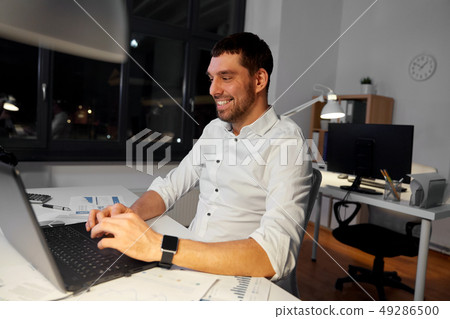 businessman with laptop working at night office 49286500