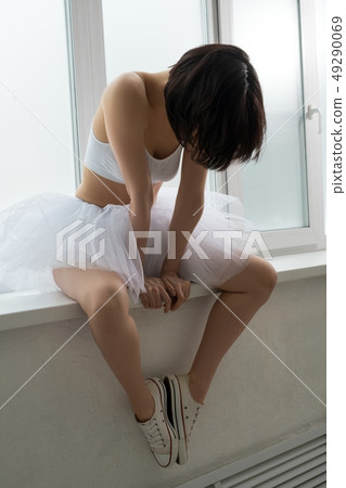 Slim woman in skirt sitting on window sill 49290069