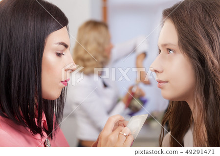 Professional makeup artist working with beautiful young woman 49291471