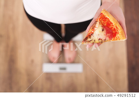 Diet. Woman Measuring Body Weight On Weighing Scale Holding Pizza. Sweets Are Unhealthy Junk Food 49291512