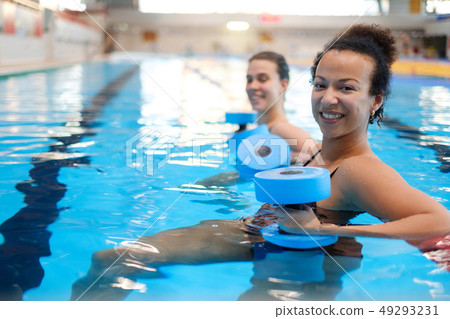 Multiracial couple attending water aerobics class in a swimming pool Multiracial couple attending water aerobics class in a swimming pool 49293231