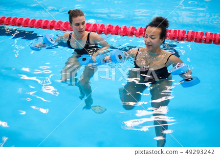 Multiracial couple attending water aerobics class in a swimming pool Multiracial couple attending water aerobics class in a swimming pool 49293242