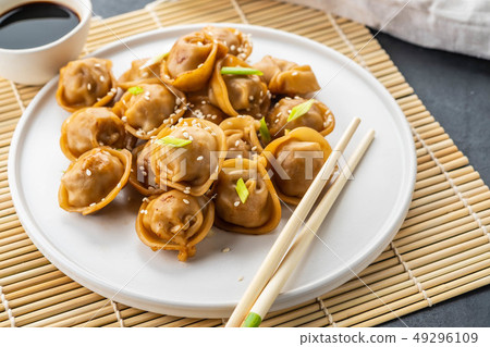 Home made chinese and korean dumplings served on the traditional steamer and bamboo mat decorated Home made chinese and korean dumplings served on the traditional steamer and bamboo mat decorated 49296109