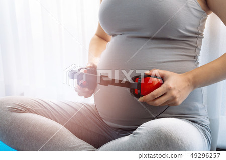 Pregnant woman letting baby in belly listen to music over window view Pregnant woman letting baby in belly listen to music over window view 49296257
