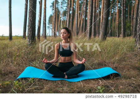 Beautiful girl sitting in summer on a rug in the forest, practicing meditation. Harmony of Beautiful girl sitting in summer on a rug in the forest, practicing meditation. Harmony of 49298718