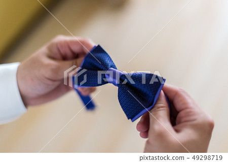 A man holds a stylish bow tie in his hands. A man holds a stylish bow tie in his hands. 49298719