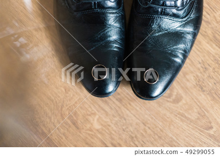 Gold wedding rings lie on the groom's shoes. 49299055