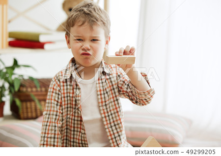 Little child sitting on the floor. Pretty boy palying with wooden cubes at home Little child sitting on the floor. Pretty boy palying with wooden cubes at home 49299205
