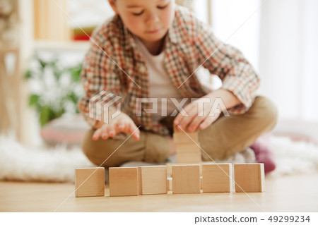 Little child sitting on the floor. Pretty boy palying with wooden cubes at home 49299234