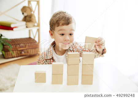 Little child sitting on the floor. Pretty boy palying with wooden cubes at home Little child sitting on the floor. Pretty boy palying with wooden cubes at home 49299248