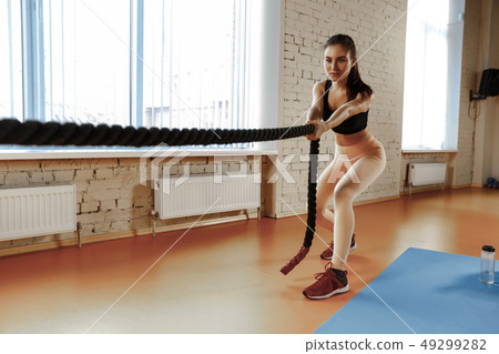 Woman with battle ropes exercise in the fitness gym. 49299282